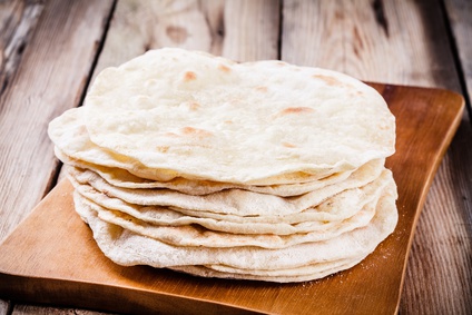 Stack of homemade wheat tortillas on wooden table